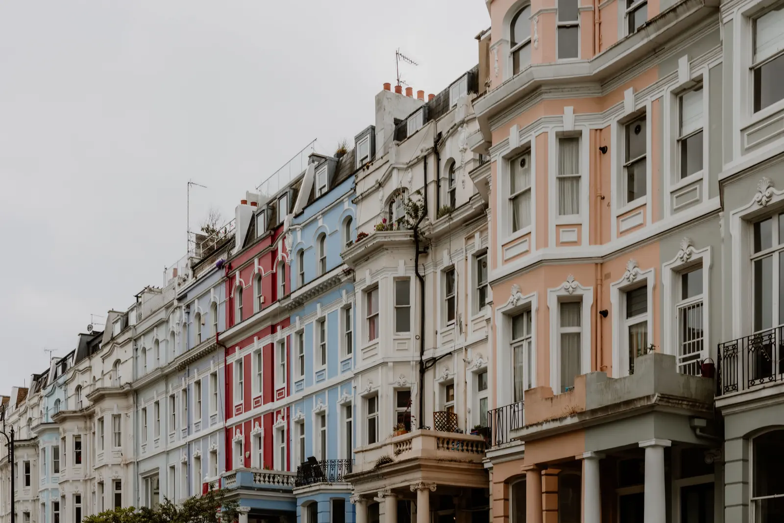 A row of pastel painted terraced houses on a quiet Notting Hill street