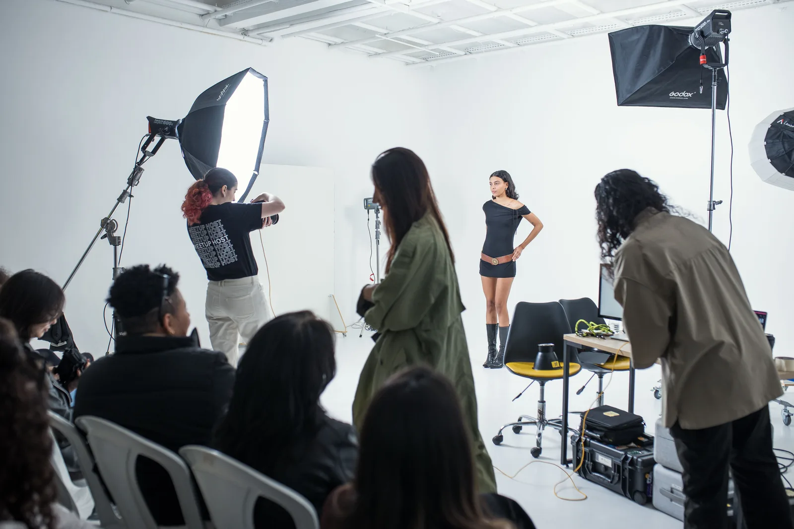 A model being photographed in a studio while others watch