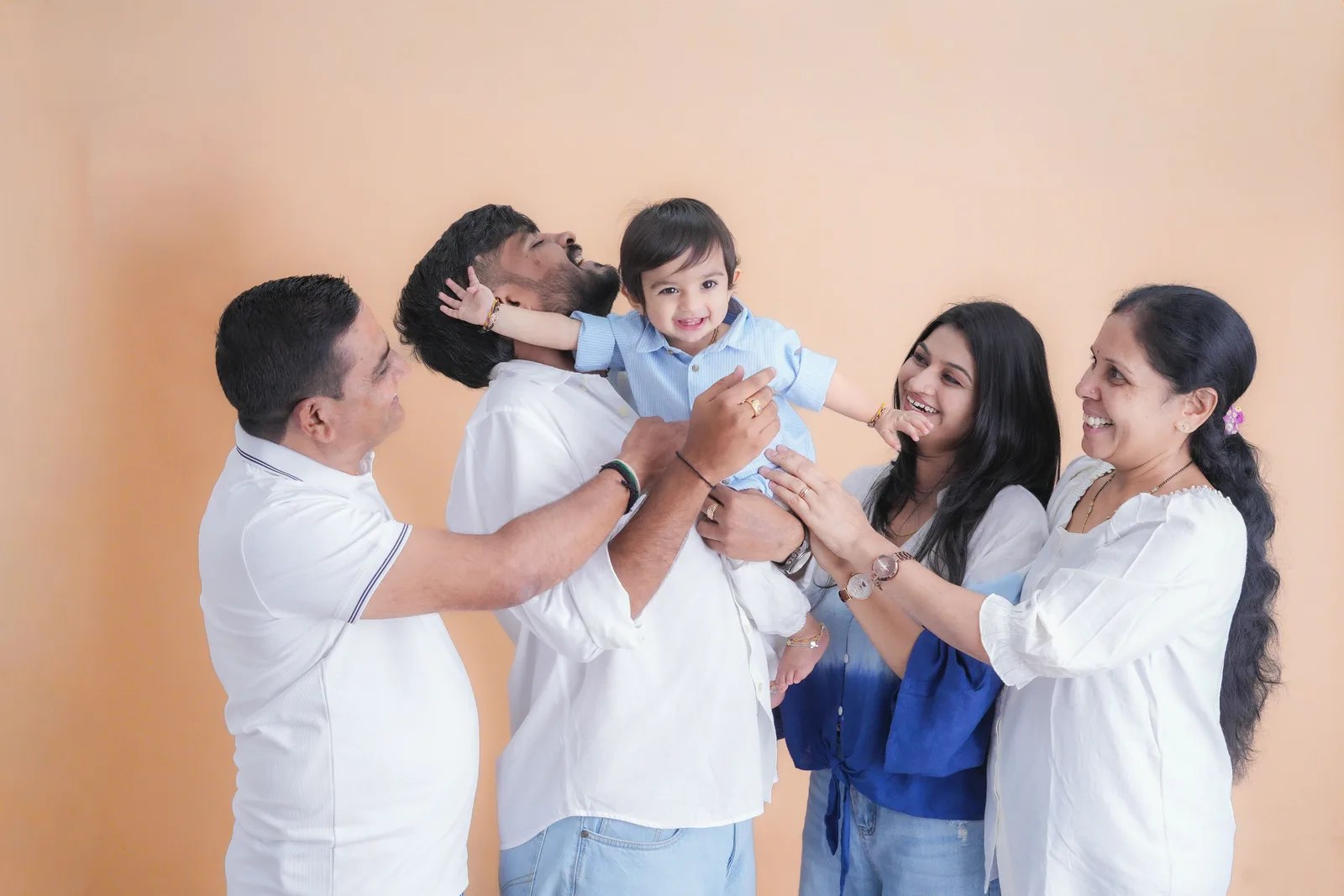 Five members of an extended family laughing together during a studio portrait