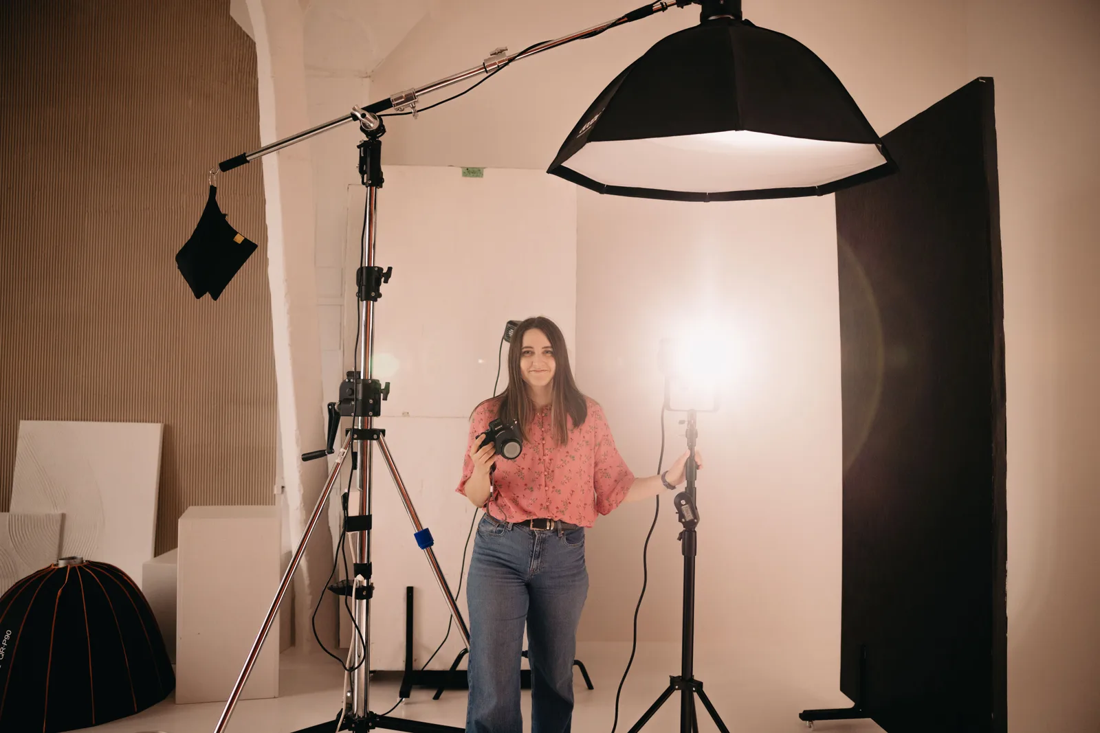 A photographer standing beside a boom mounted softbox in a bright studio