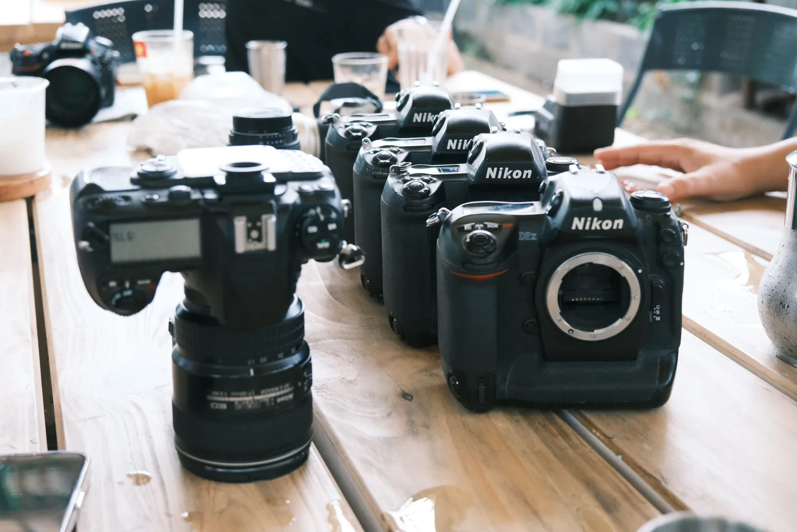 Four camera bodies and a lens lined up on a table