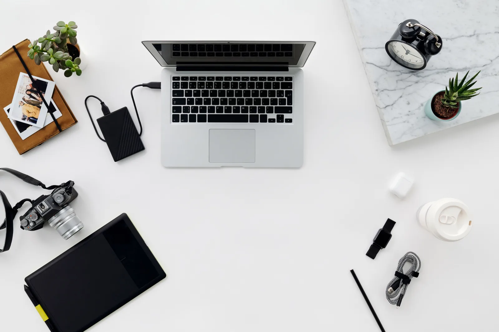 A laptop, a portable drive and a camera laid out on a desk