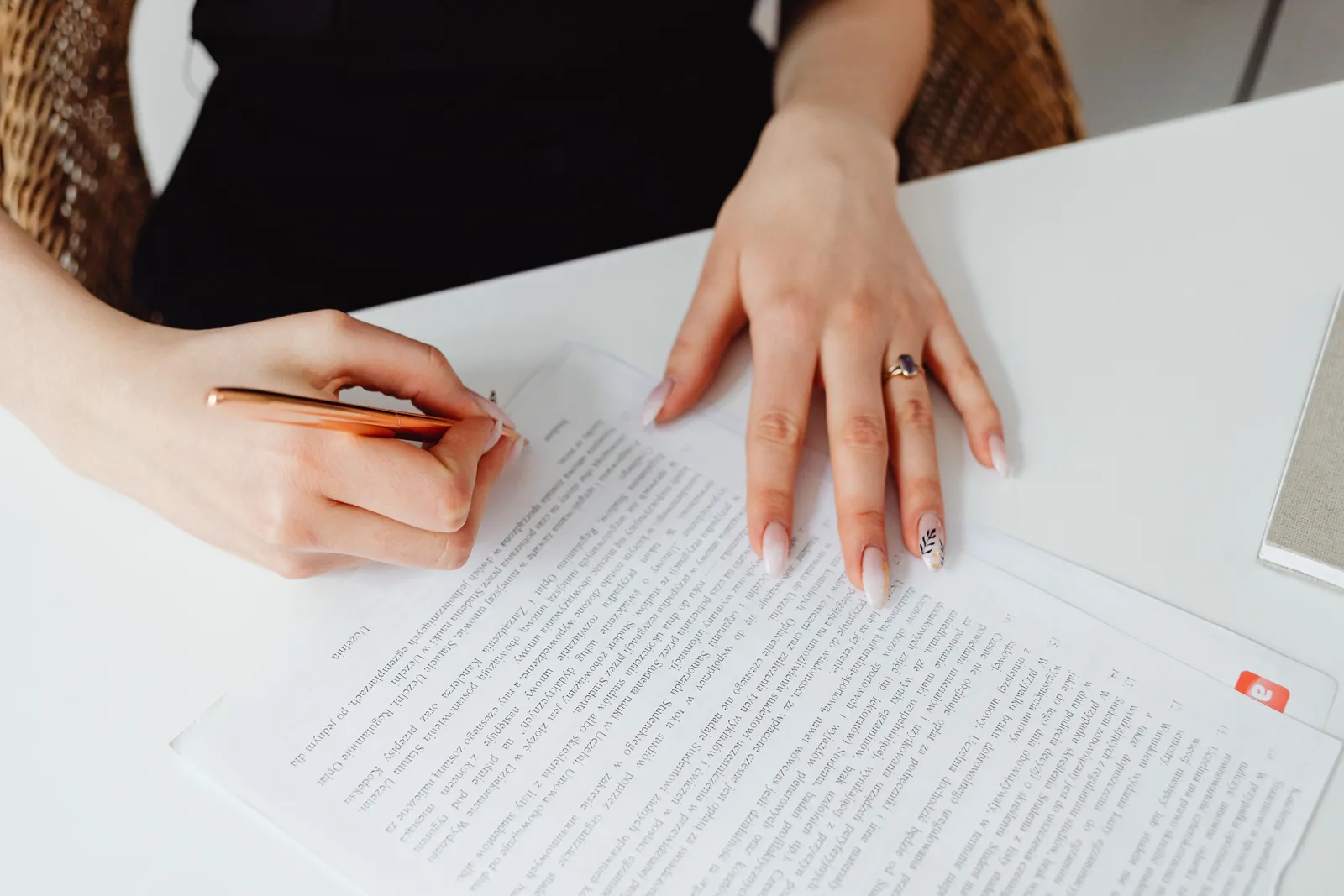 A woman signing a printed document with a pen at a desk