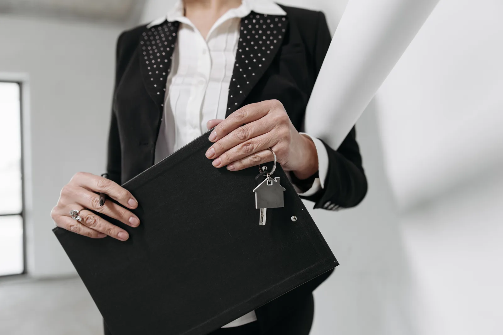 An estate agent holding a folder and a set of house keys