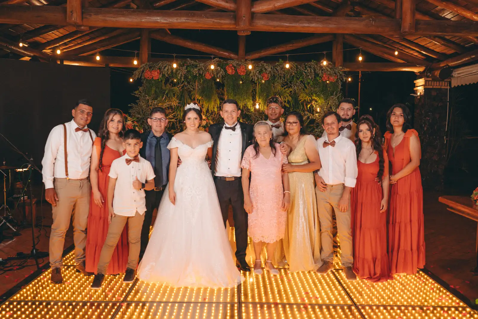 A wedding family group posed together on a lit dance floor