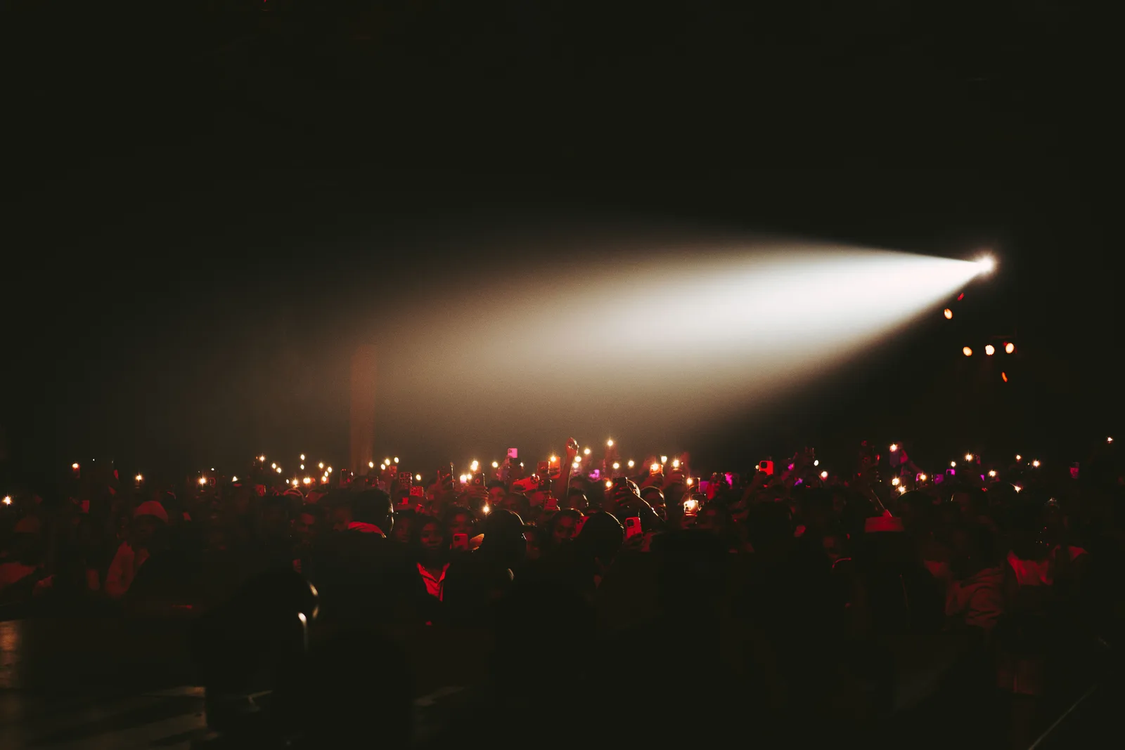 A beam of light cutting across a dark, crowded venue