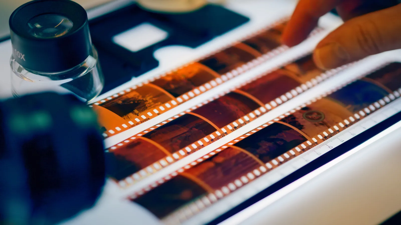Strips of film negatives laid out on a light table with a loupe