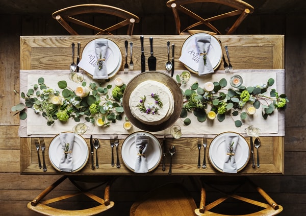 Overhead view of a set dinner table with greenery down the middle and a napkin on each plate