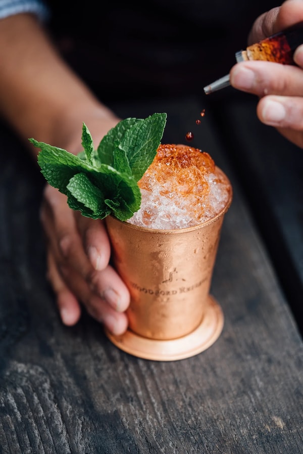A bartender garnishing a copper cup of crushed ice and mint