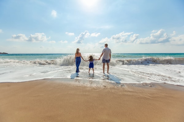 Parents walking into the surf with their daughter between them