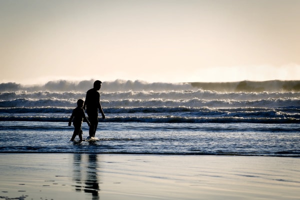 Silhouette of a father and child paddling in the waves