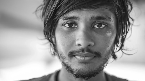 Black and white close portrait of a young man with tousled hair looking into the lens
