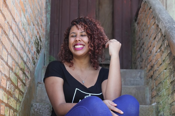 Woman with curly red hair laughing on a narrow brick stairway