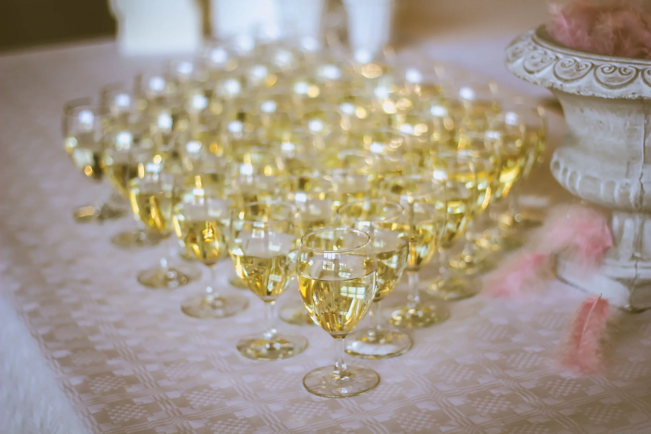 Rows of filled champagne glasses on a white tablecloth, waiting for the toast