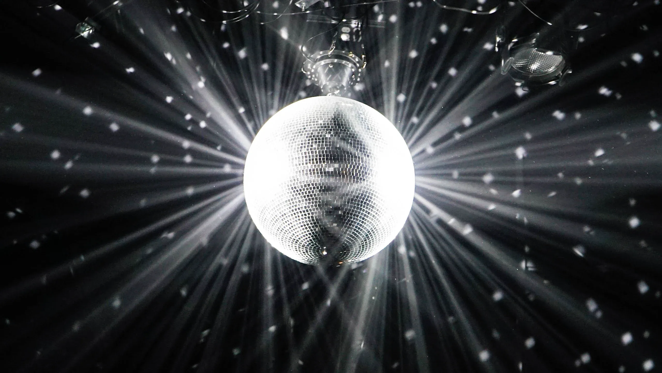 A mirror ball throwing white rays across a dark ceiling