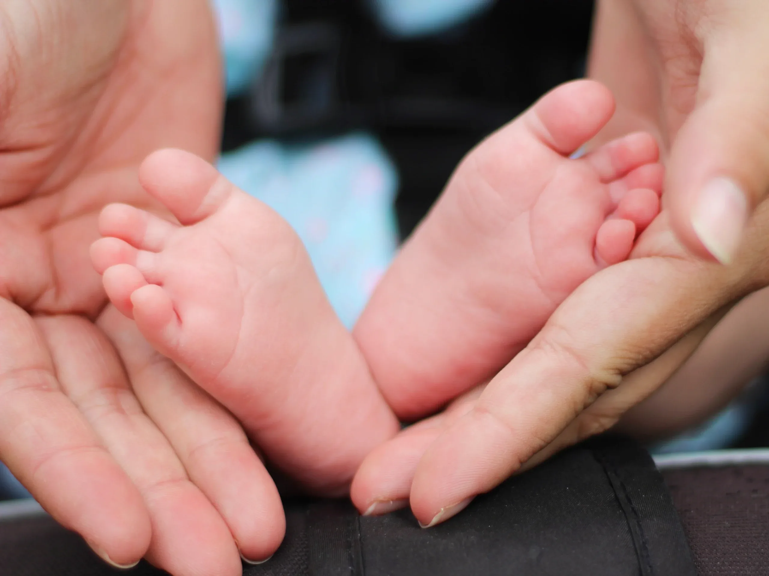 Two tiny feet resting in a parent’s open palms