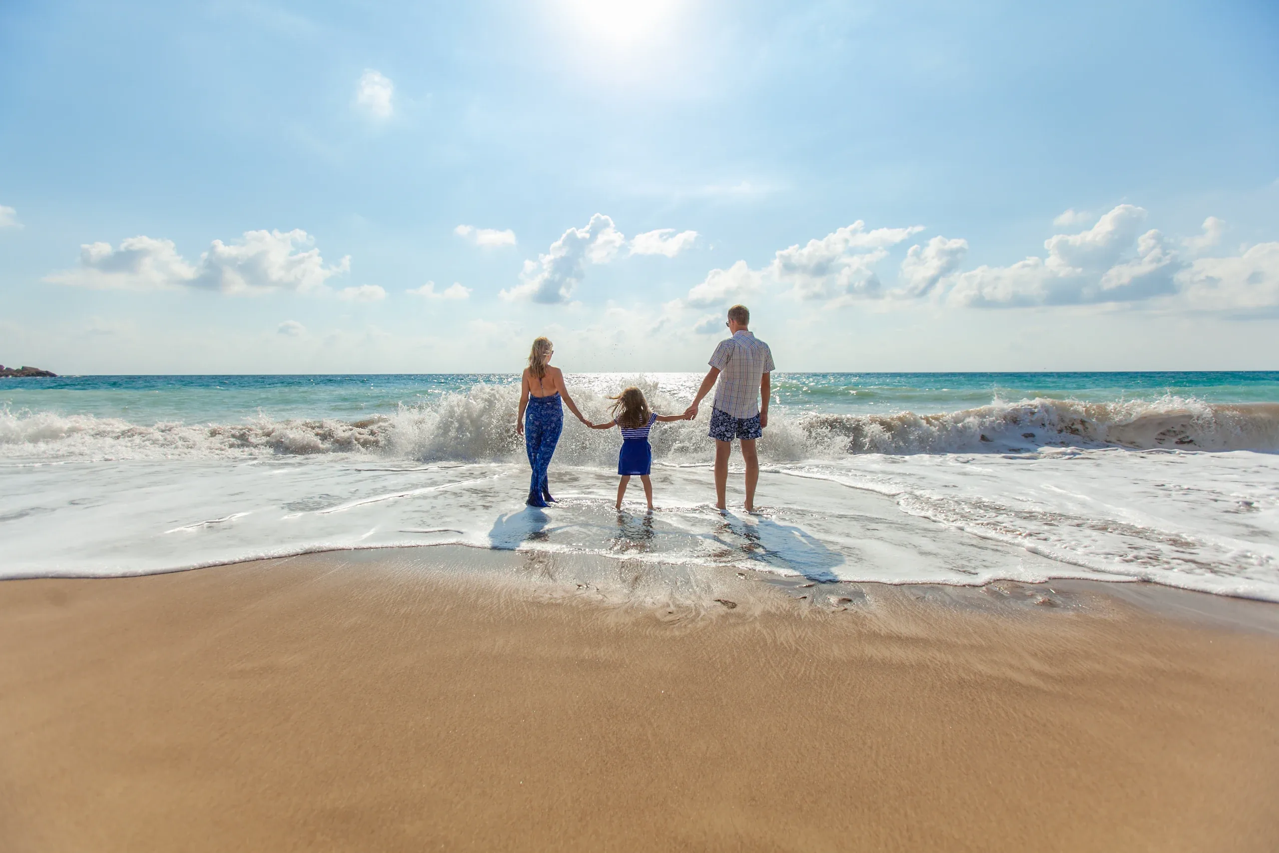 Parents walking into the surf with their daughter between them