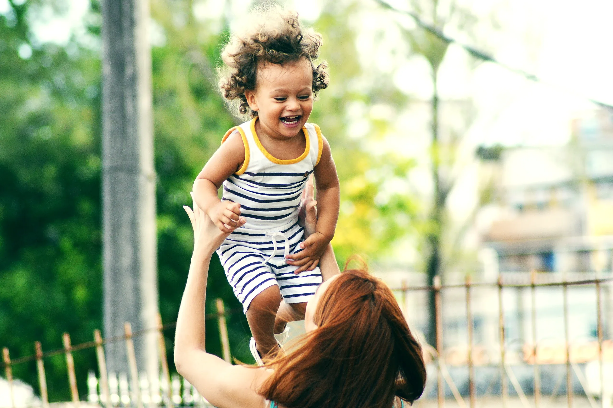 Mother throwing her delighted toddler up into the air