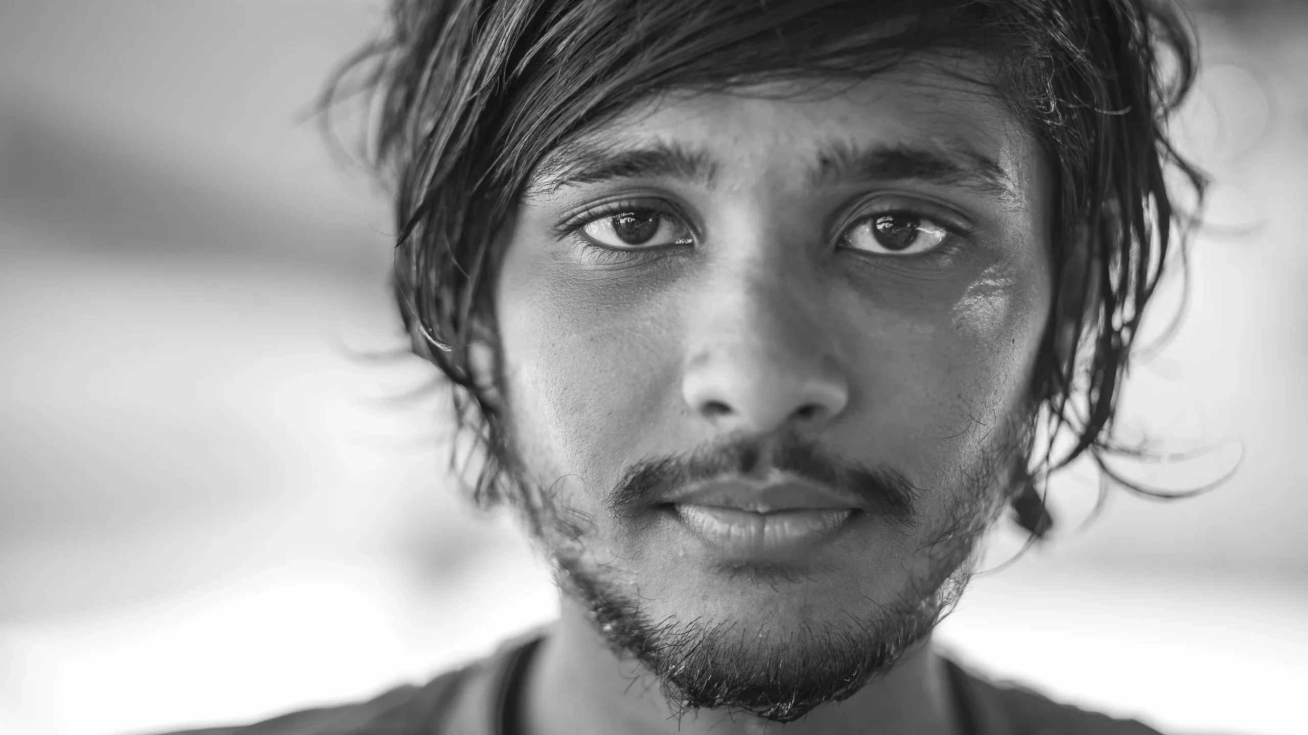 Black and white close portrait of a young man with tousled hair looking into the lens