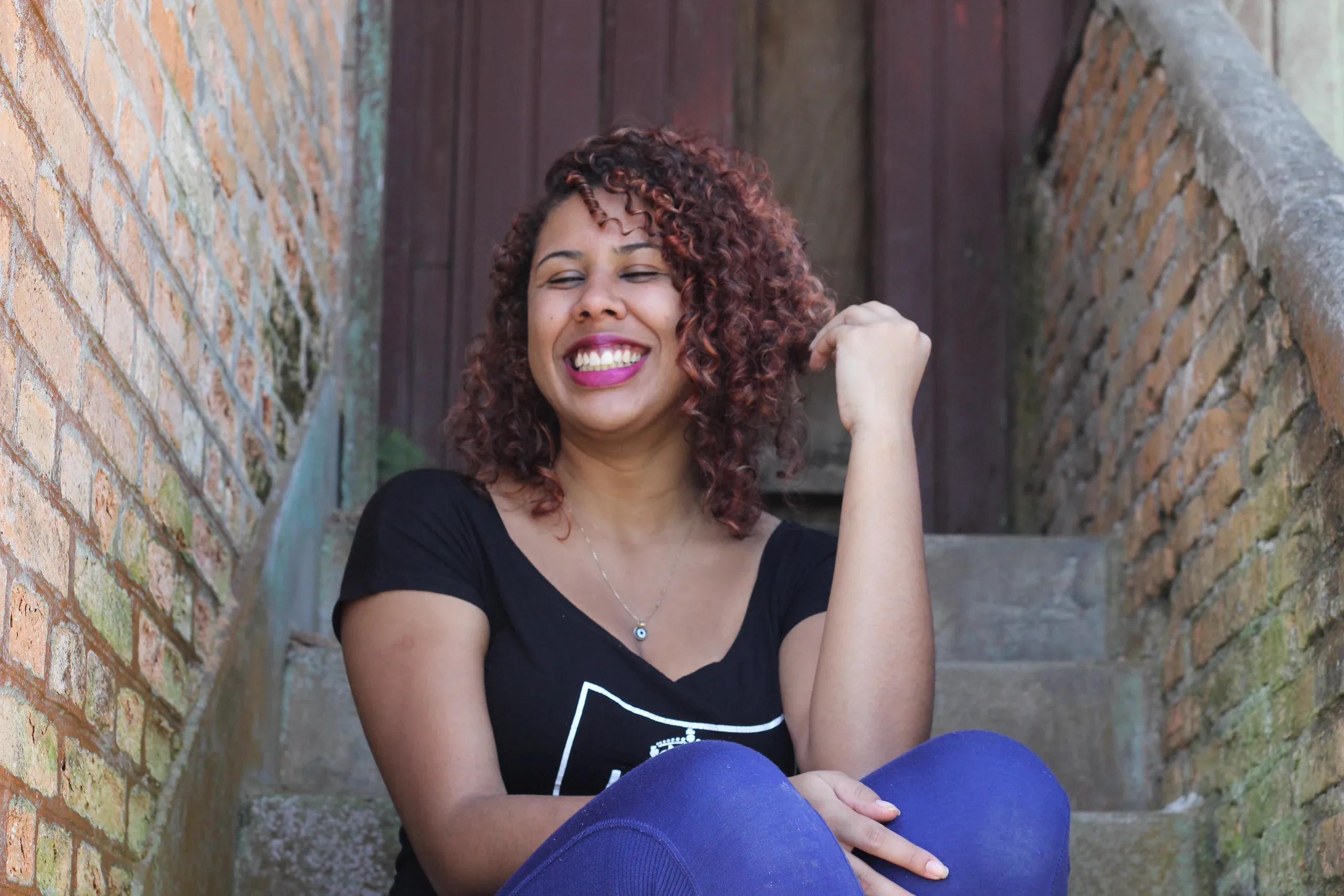 Woman with curly red hair laughing on a narrow brick stairway